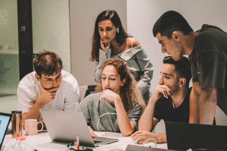 People working together around a table looking at a laptop